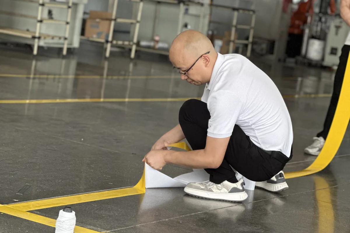 Installing yellow floor marking tape in a factory